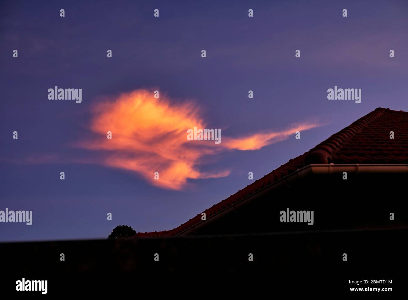 El cielo dramático por la noche con el sol que pone creando un efecto de nube ardiente naranja dramático Foto de stock