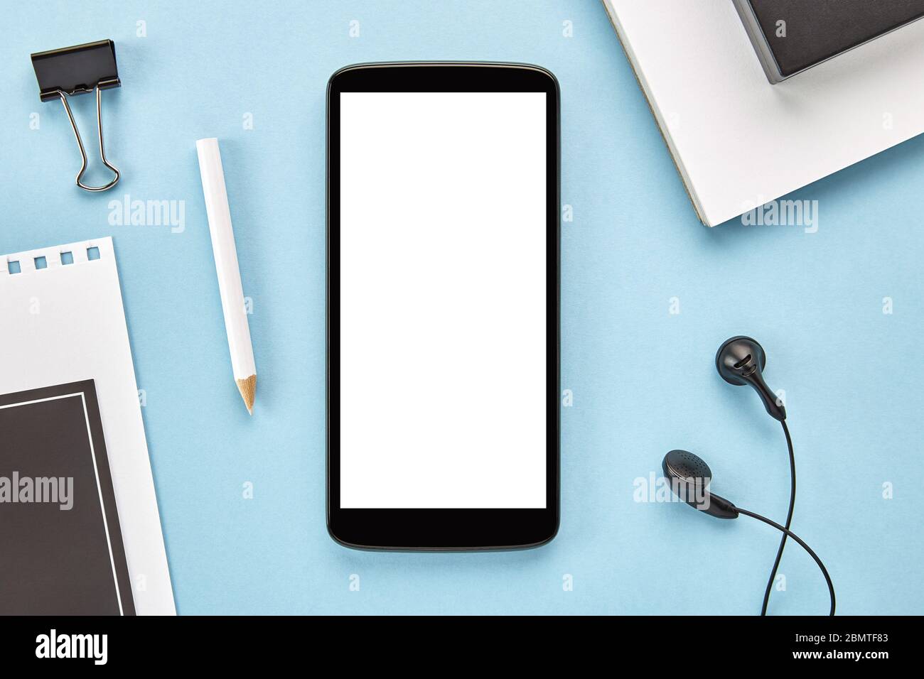 Imagen de un smartphone con pantalla blanca en blanco sobre una superficie azul. Disposición plana Foto de stock