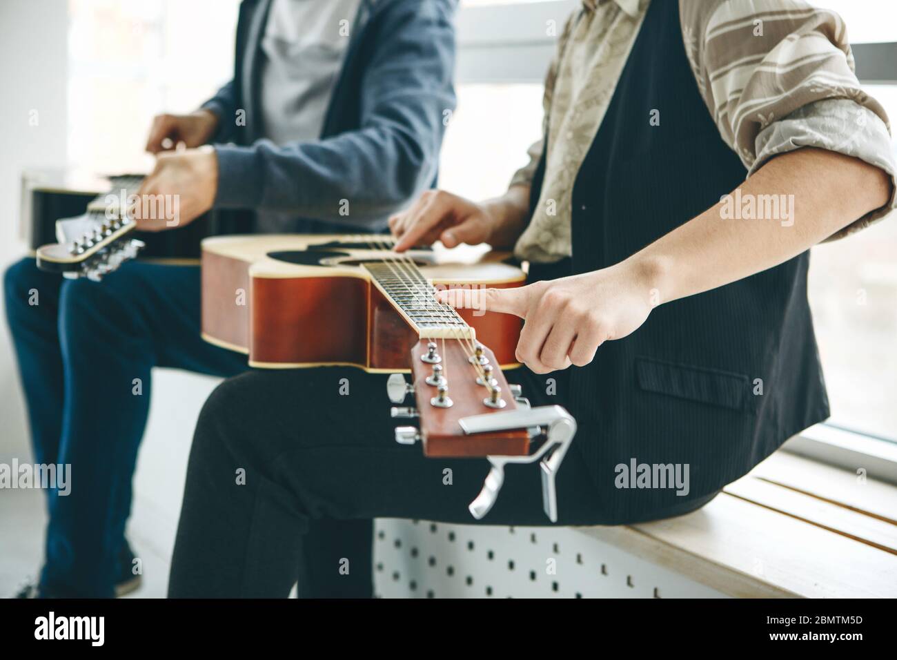 Aprender a tocar la guitarra. El profesor ayuda al estudiante a afinar la  guitarra y explica los fundamentos de tocar la guitarra. Educación  individual en el hogar o lecciones extracurriculares Fotografía de