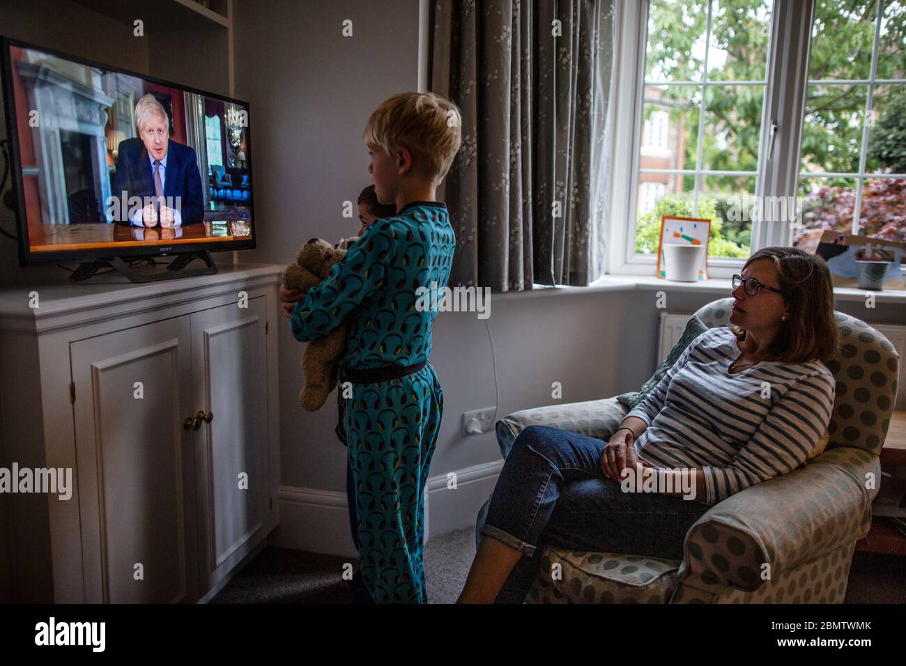 Familia observa al primer ministro Boris Johnson dirigirse a la nación británica en la televisión nacional, estableciendo pasos de un "mapa de carreteras" para salir del bloqueo del Coronavirus Foto de stock