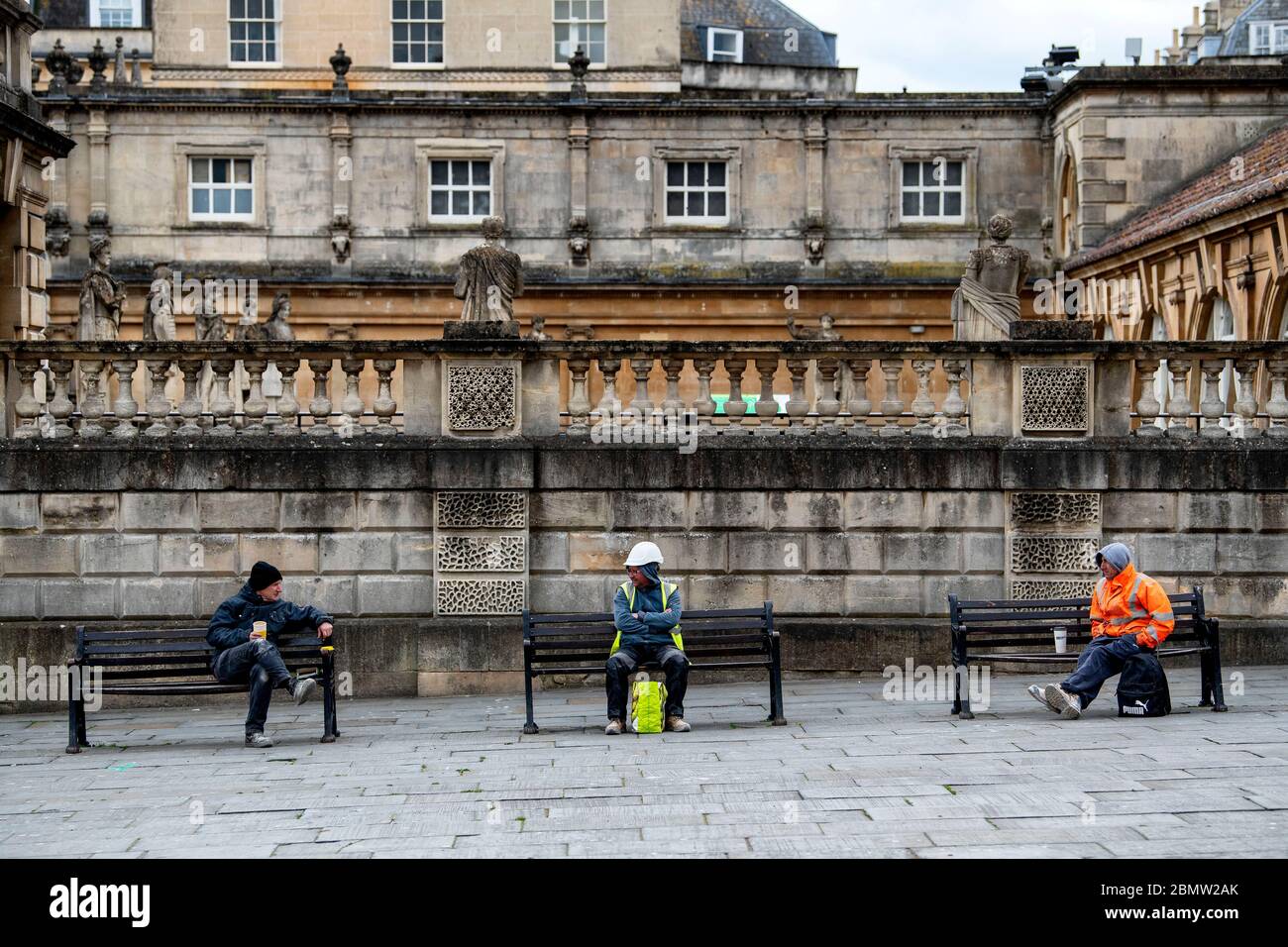 Los trabajadores de la construcción se distancian socialmente mientras toman un descanso fuera de los Baños Romanos en Bath, Somerset, mientras el gobierno británico restringe las restricciones de cierre. Foto de stock