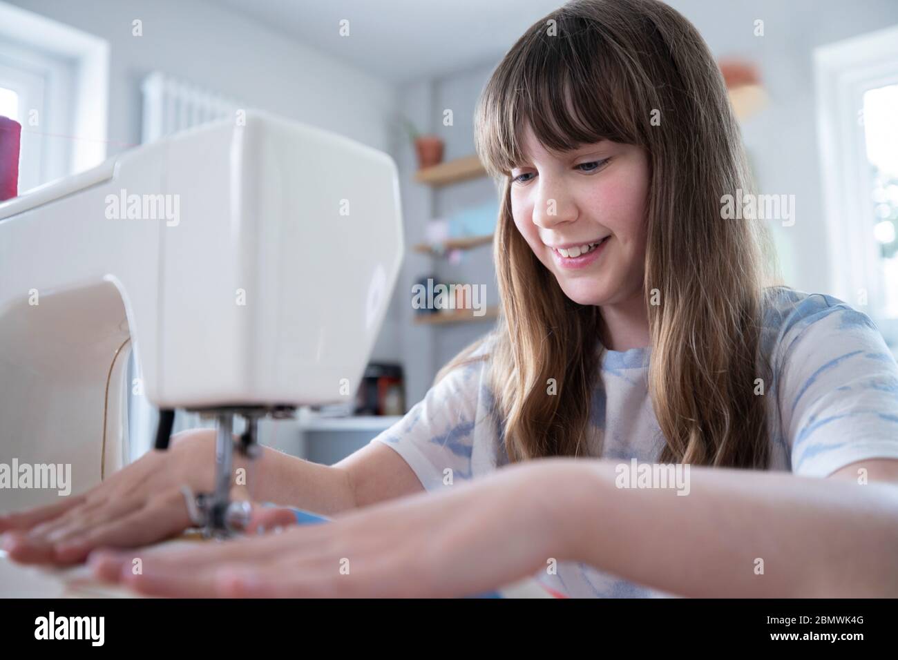 Niña aprendiendo como usar la máquina de coser en casa Foto de stock