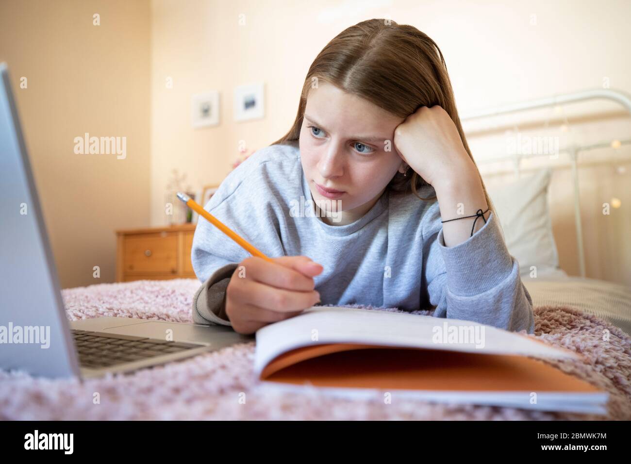 Adolescente estresado que tiene problemas para usar el ordenador portátil para tareas domésticas o para la escolarización en casa Foto de stock