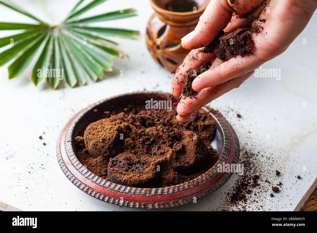 La mano de la mujer desmenuza los granos de café en un tazón de madera. Café  molido usado como un exfoliante corporal o fertilizante para plantas  Fotografía de stock - Alamy