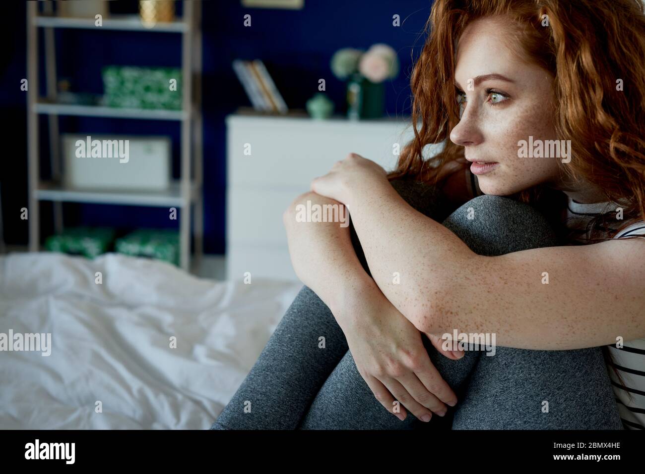Mujer pensativa de pelirroja en su cama Foto de stock