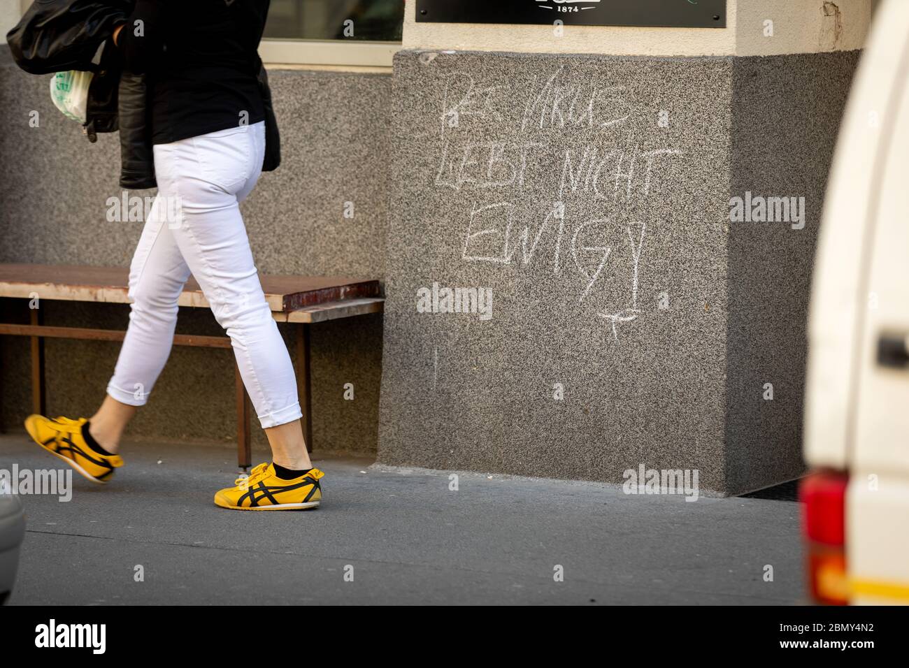 Viena, Austria-Abril 20,2020: Cerca de las piernas de las mujeres pasando un signo escrito a mano en lengua alemana diciendo: El virus no vive para siempre Foto de stock