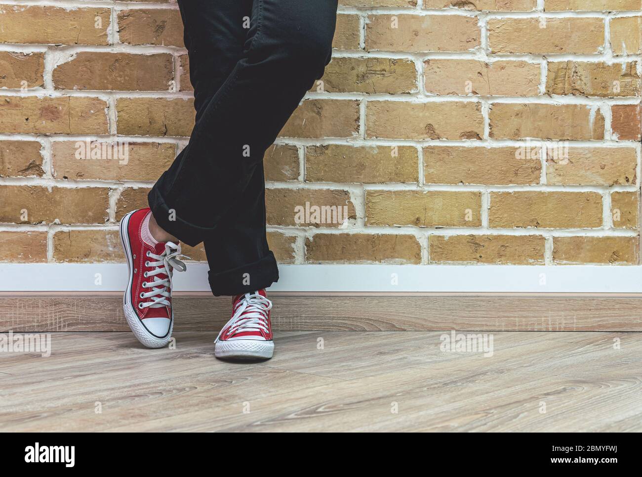 Mujer piernas en jeans y zapatillas de deporte rojas, mujer de pie frente a  la pared de ladrillo, concepto de moda Fotografía de stock - Alamy