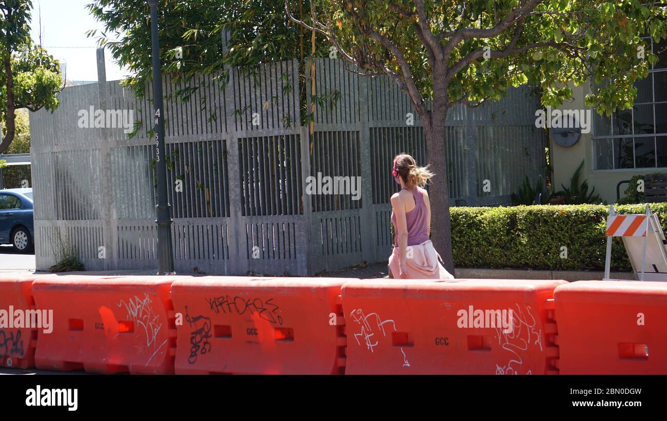 Mujer caminando con auriculares en calle cerrada reservado para peatones sólo para apoyar el distanciamiento social debido a COVID19. Emeryville, CA, EE.UU. Foto de stock