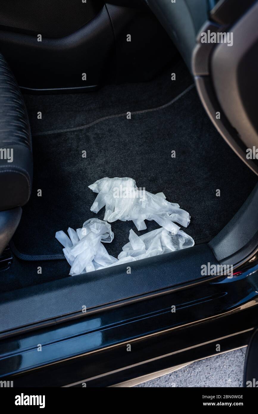 Guantes de plástico desechables en alfombra de piso de coche durante la pandemia de Covid-19. Foto de stock