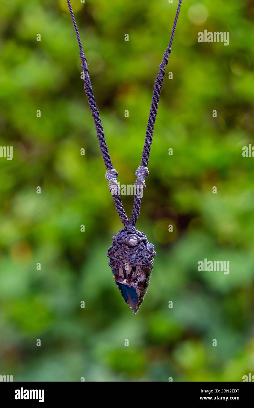 Abundancia Disgusto hecho Macrame piedras minerales obsidiana collar sobre fondo verde natural bokeh  Fotografía de stock - Alamy