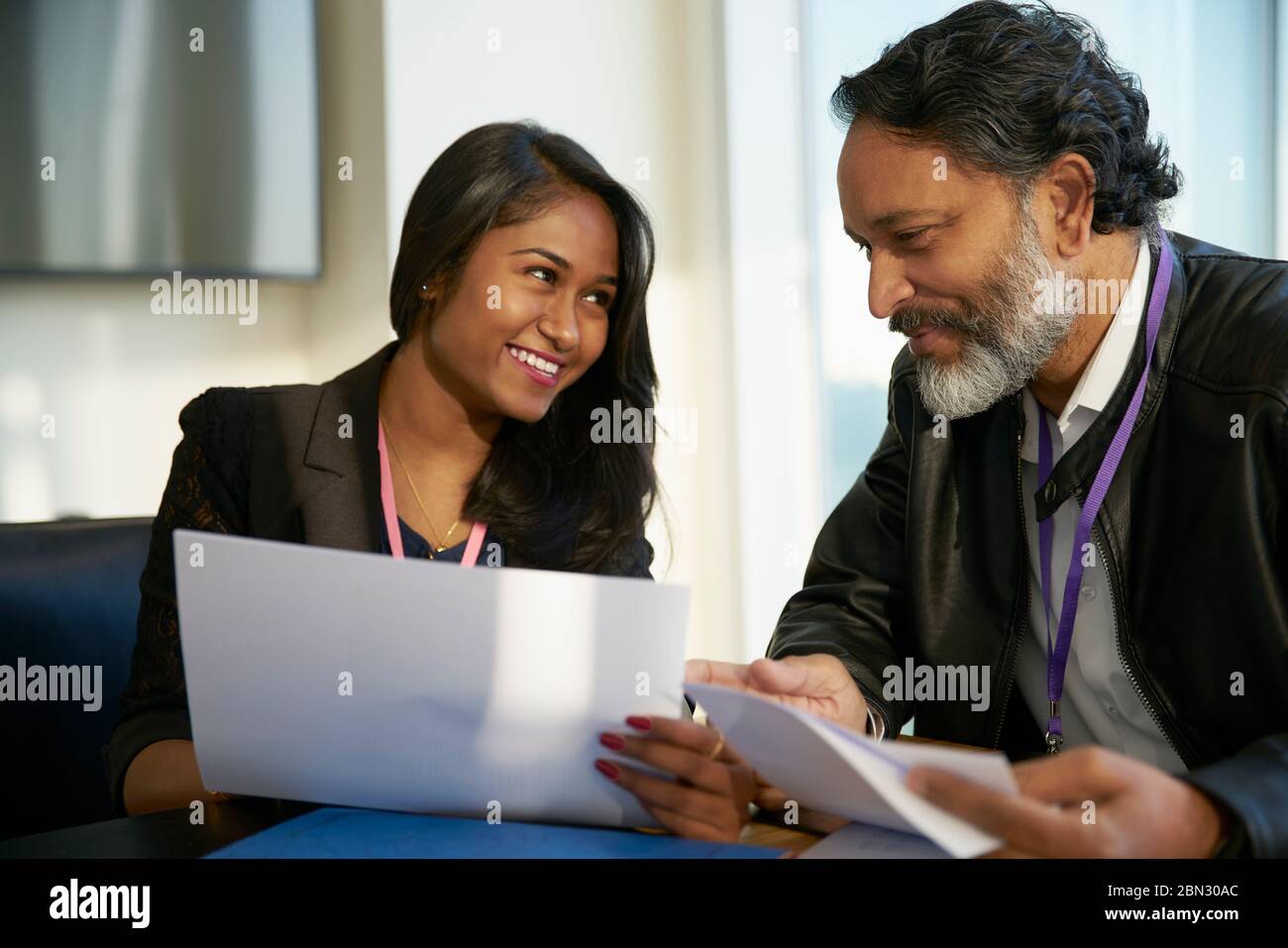 Negocios sonriendo gente discutiendo el papeleo en reunión Foto de stock