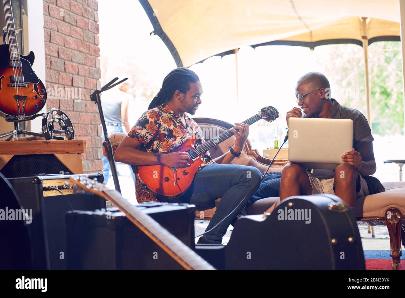 Músicos masculinos con portátil y guitarra eléctrica en taller de grabación Foto de stock