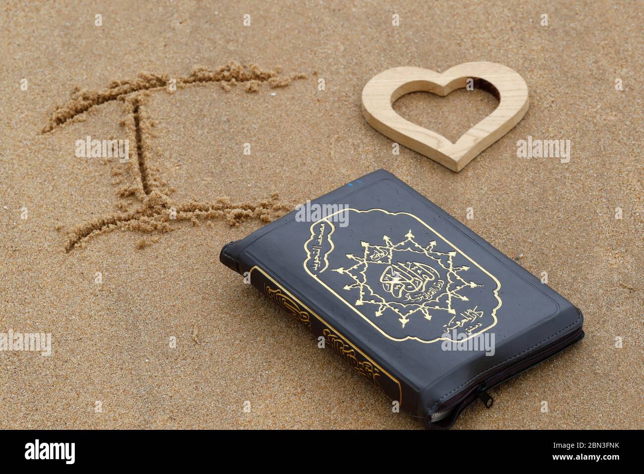 Abra el Corán en la arena con el corazón. Amo Quran. Francia. Foto de stock