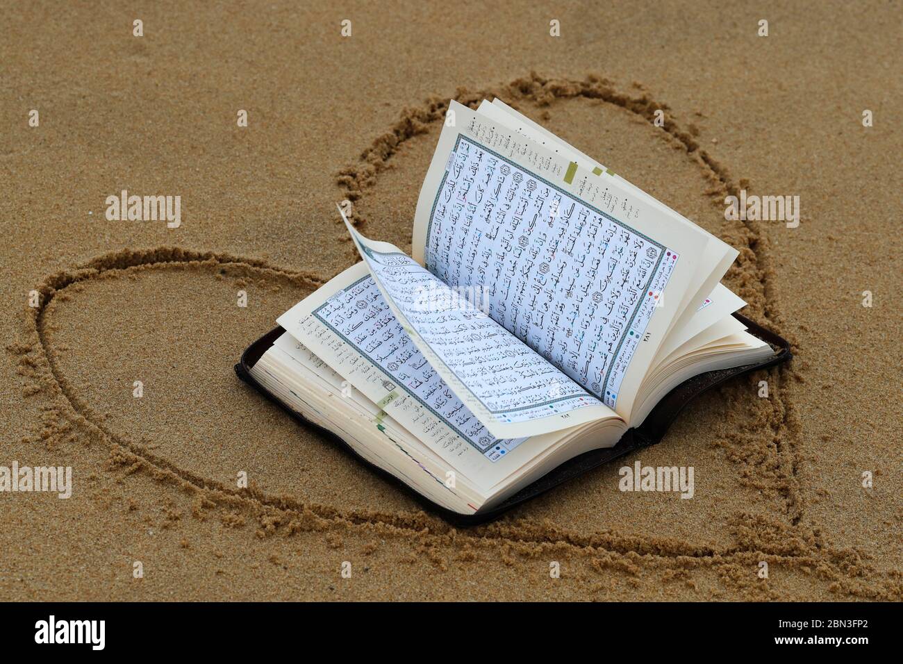 Abra el Corán en la arena con el corazón. Francia. Foto de stock
