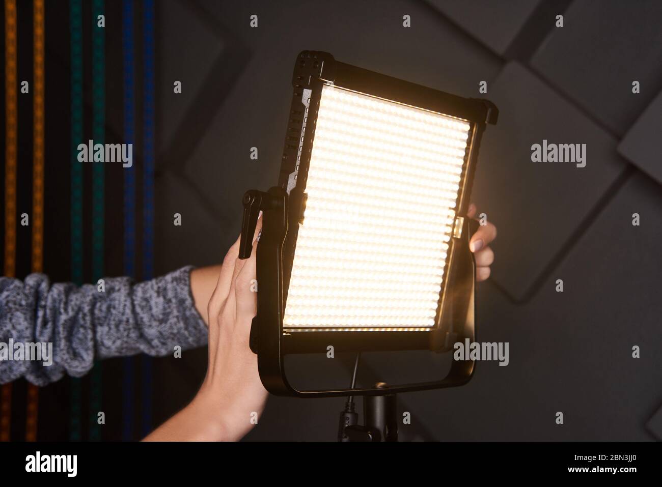 asistente de estudio fijar luz de vídeo profesional en soporte de luz  ajustable. Lámpara LED en trípode en estudio fotográfico. Lámpara de fotos  y vídeo en gris Wal en relieve Fotografía de