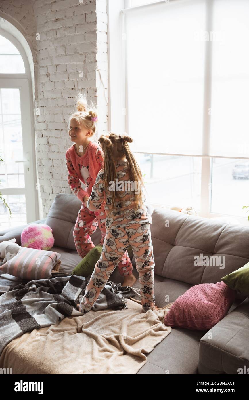 Chicas pequeñas y tranquilas jugando en un dormitorio con un bonito pijama,  estilo casero y comodidad. Lindas chicas caucásicas a primera hora de la  mañana, dulces sueños. Concepto de infancia, felicidad, amistad,
