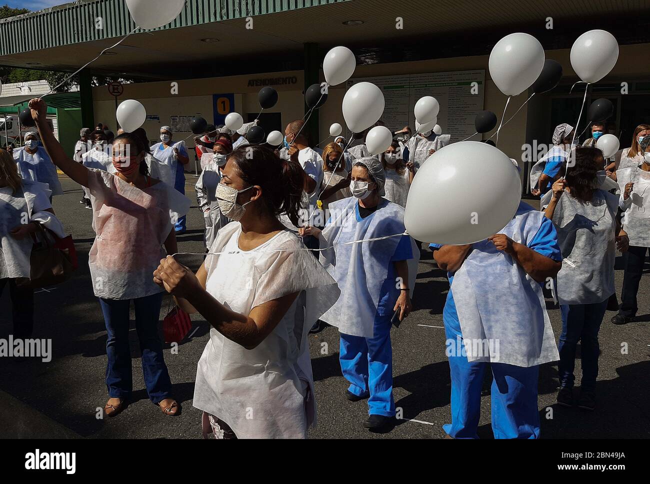 Sao Paulo, Brasil. 12 de mayo de 2020. 12 de mayo de 2020: Unos 50 profesionales esenciales de la salud detuvieron sus actividades para protestar con globos en frente del Hospital Universitario de Sao Paulo. Los manifestantes, además de sostener globos blancos y negros, llevaban chalecos con cruces negras y caminaban por el hospital. Crédito: Dario Oliveira/ZUMA Wire/Alamy Live News Foto de stock