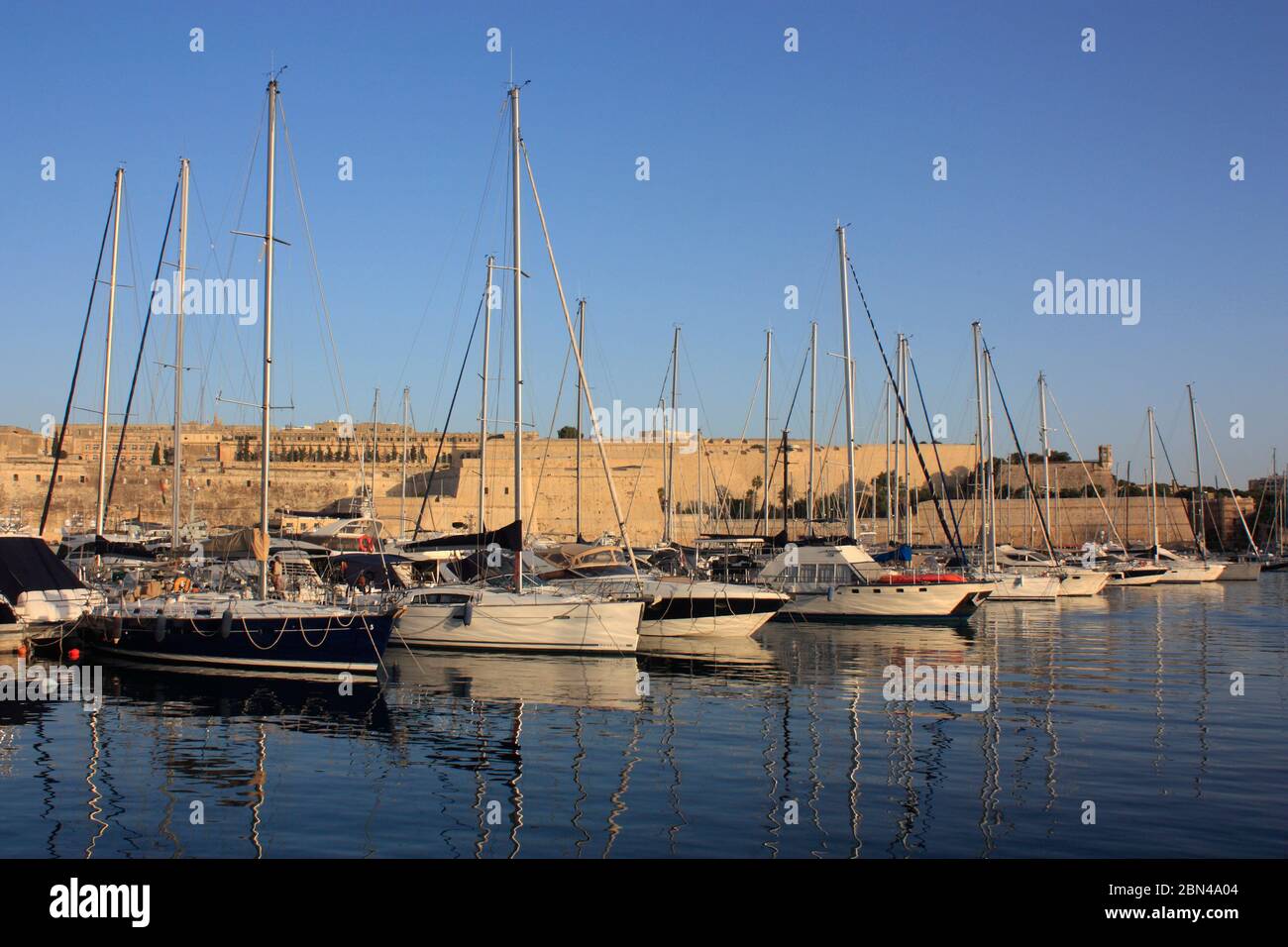 Yates amarrados en ta' Xbiex Yacht Marina, Malta, con las fortificaciones de Floriana en el fondo. Navegación en el Mar Mediterráneo. Foto de stock