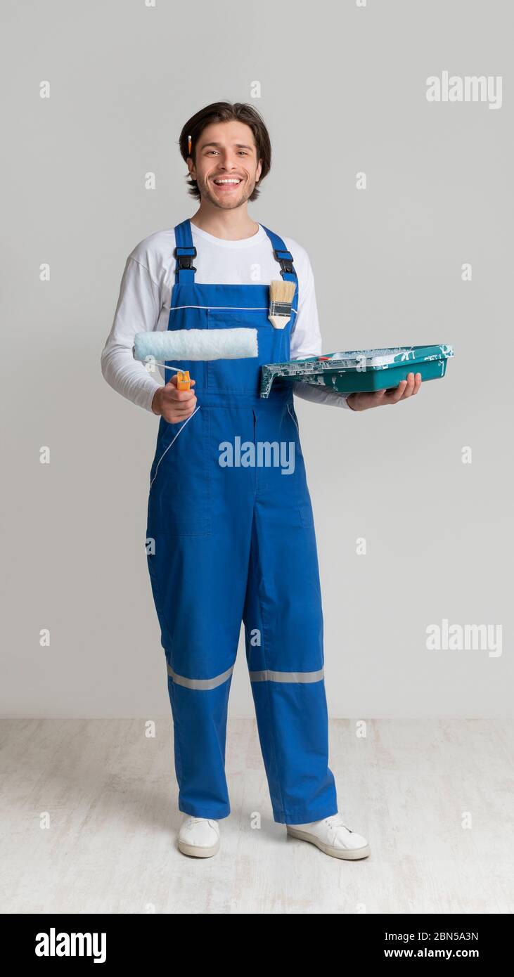 Pintor profesional en el trabajo uniforme sosteniendo el rodillo de pintura  y el ordeño en la cámara Fotografía de stock - Alamy