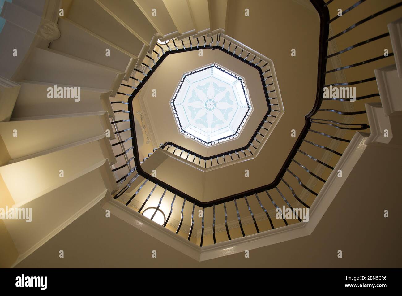 Vista desde la parte inferior de una escalera de caracol que da al punto central en el techo de una ventana art deco, Foto de stock