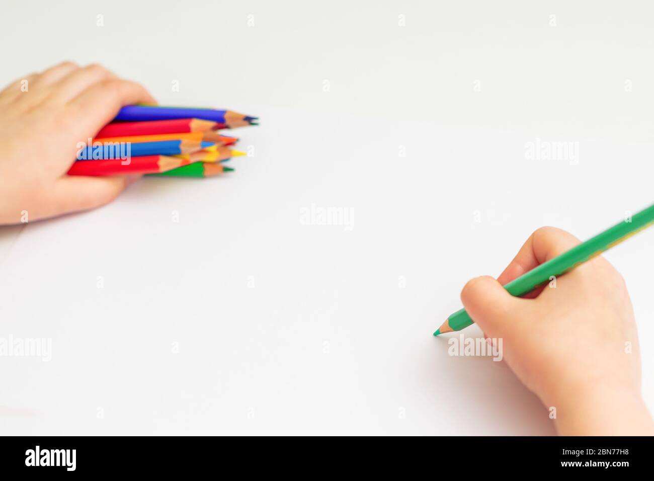 Dibujo de la mano del niño con lápiz de color en papel blanco sosteniendo  un montón de lápices de colores en su mano. Enfoque selectivo Fotografía de  stock - Alamy