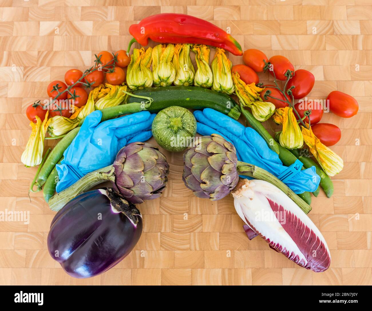 Arco iris de verduras símbolo de esperanza Covid-19 pandemia de Coronavirus: Tomates, flores de calabacín, guisantes, alcachofas, endivias, berenjena, guantes quirúrgicos Foto de stock