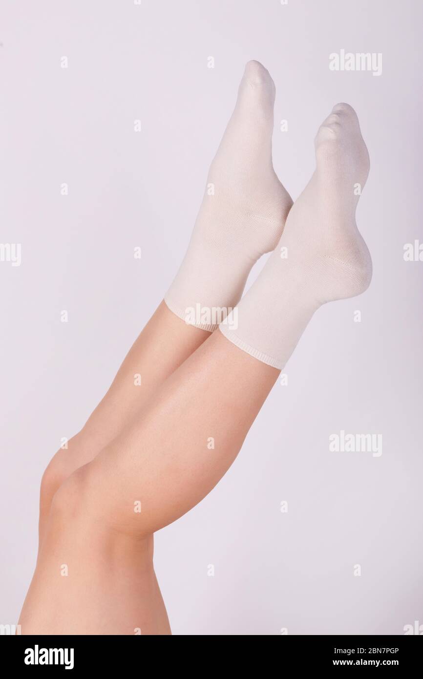 Patas femeninas en calcetines de algodón blanco sobre fondo blanco. Mujeres con calcetines deportivos Foto de stock