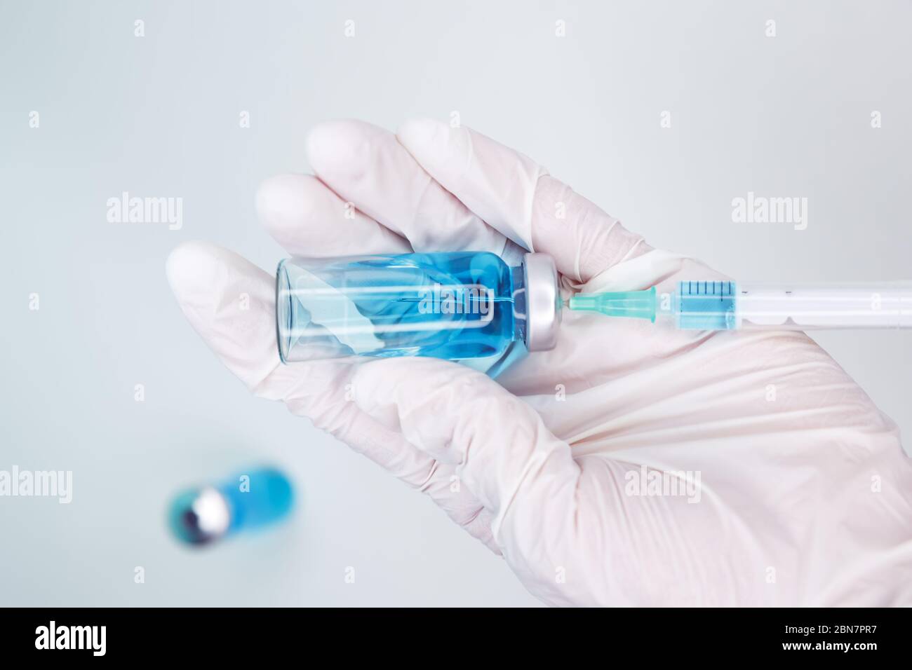 El médico recoge el medicamento de una ampolla en una jeringa. Vial de vacuna Foto de stock