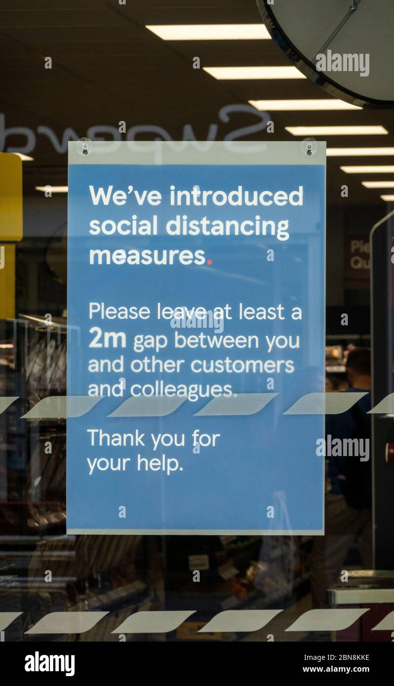 Señal de advertencia sobre distanciamiento social en la ventana de un supermercado de Liverpool Foto de stock
