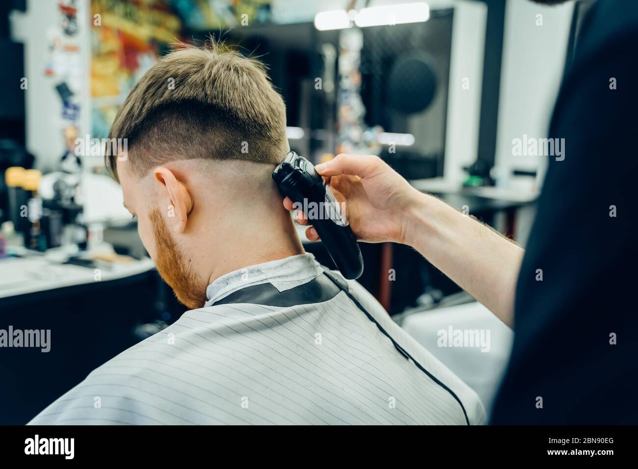 Corte de pelo macho con navaja eléctrica. Barber hace corte de pelo para el  cliente en la tienda de barbería utilizando el cortapelos. Hombre de  peluquería con afeitadora eléctrica Fotografía de stock -