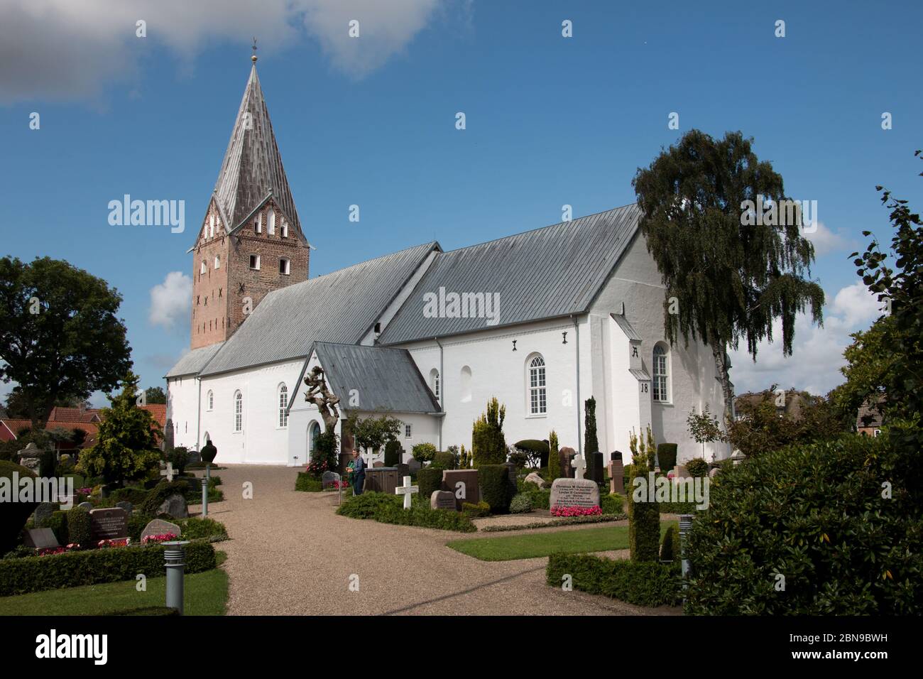 Tonder, Dinamarca - 20 de agosto de 2019: Mogeltonder iglesia con paredes blancas y un gran campanario y un cementerio a su alrededor en una pequeña ciudad de Dinamarca. Cátodo Foto de stock
