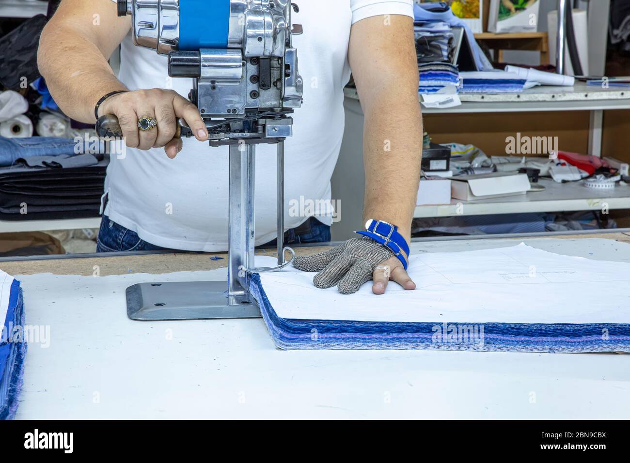 marxismo Cava Persona australiana Trabajador que usa un cortador - una gran máquina para cortar telas - en  una fábrica textil, lleva un guante de cadena Fotografía de stock - Alamy