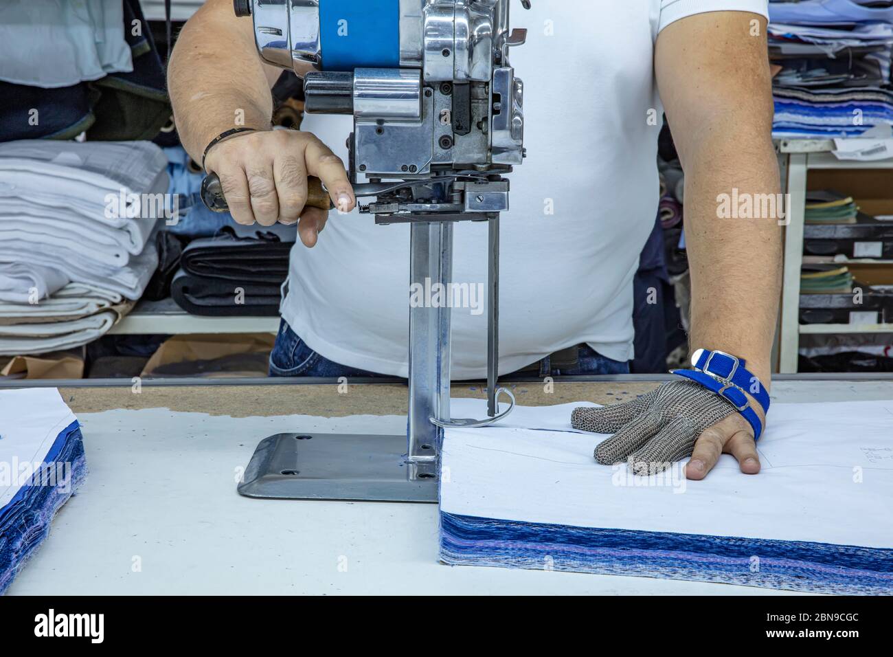 Trabajador que usa un cortador - una gran máquina para cortar telas - en  una fábrica textil, lleva un guante de cadena Fotografía de stock - Alamy