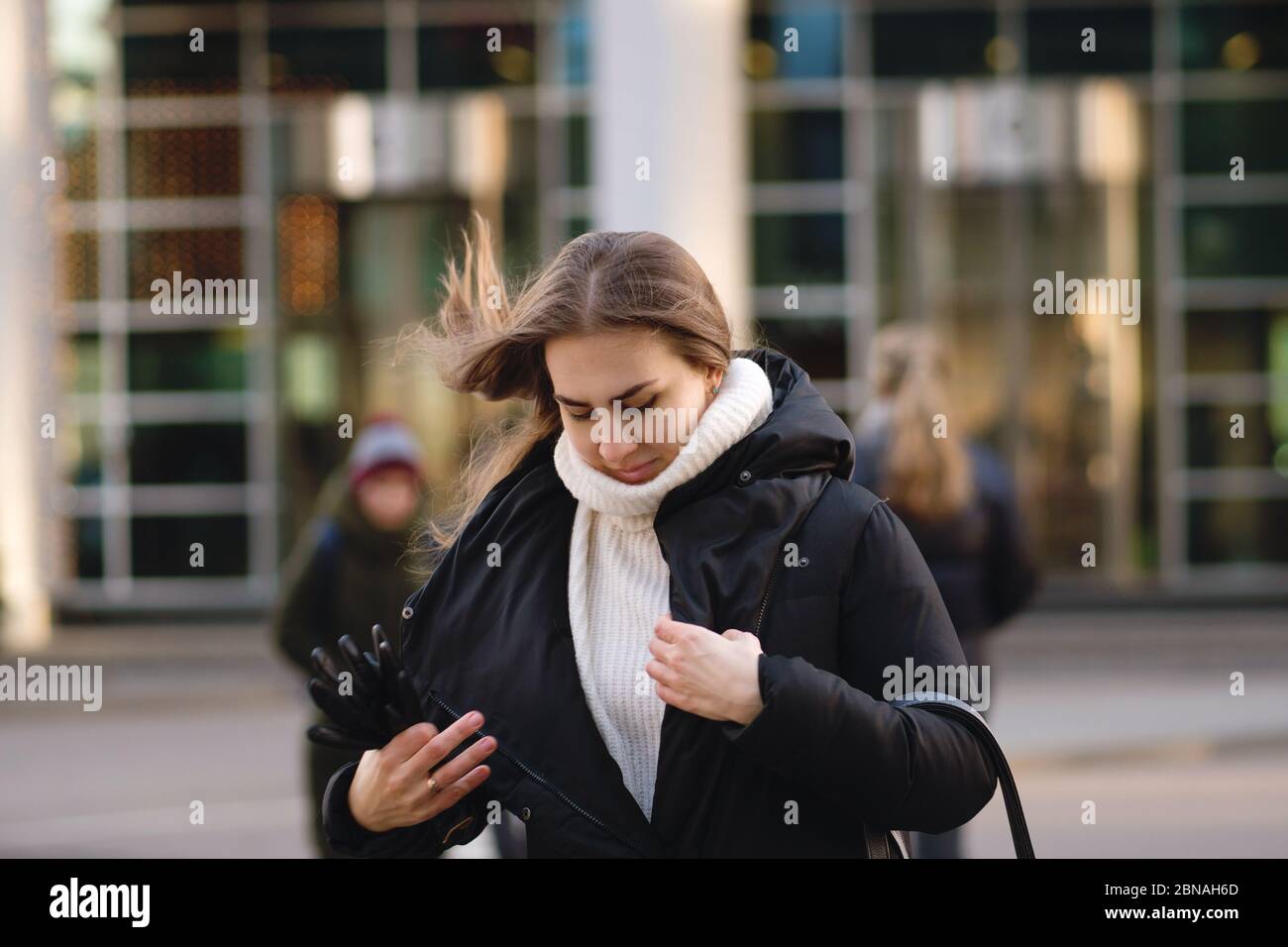 Retrato de una mujer bonita moderna y ocupada. Chica hurta y sujeta ropa  exterior en movimiento. El cabello se desarrolla en el viento. Fondo centro  de negocios Fotografía de stock - Alamy