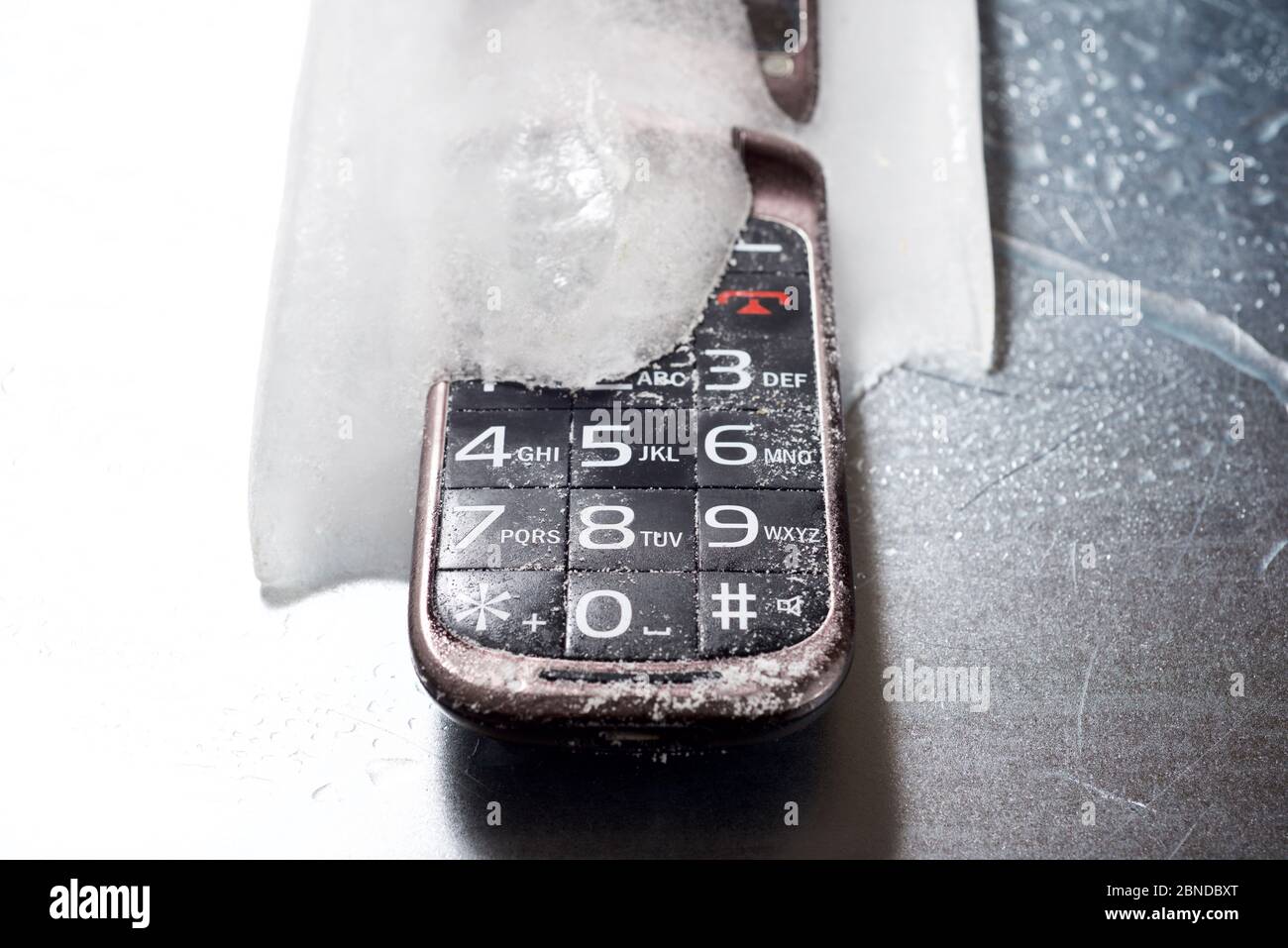 Viejo teléfono móvil congelado en una mesa de metal Fotografía de stock -  Alamy