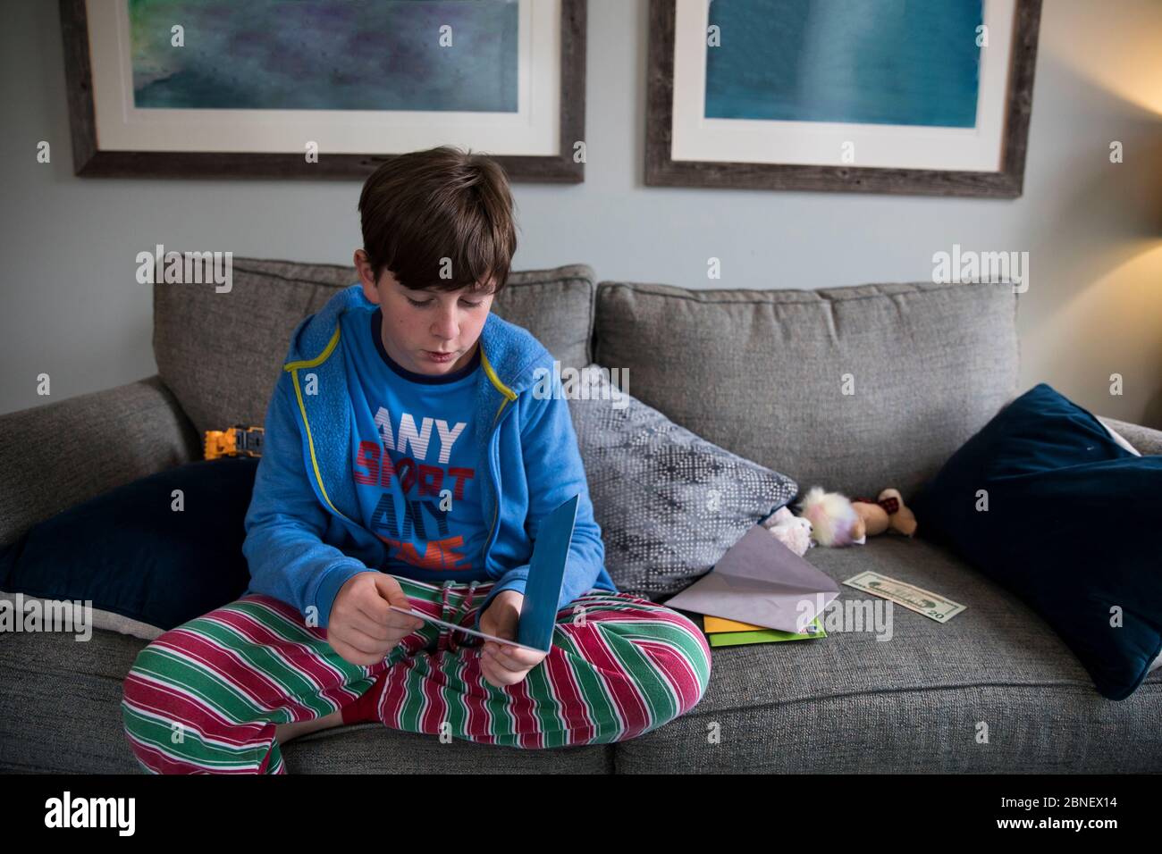 Pijama de niño adolescente a rayas que lee la tarjeta de cumpleaños  mientras está sentado En la camilla Fotografía de stock - Alamy