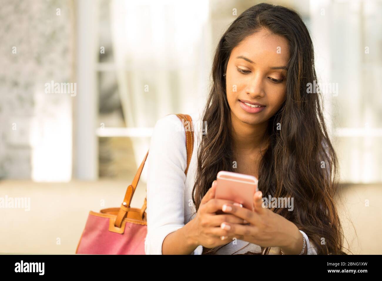Mujer joven hablando y escribiendo mensajes en su teléfono móvil. Foto de stock