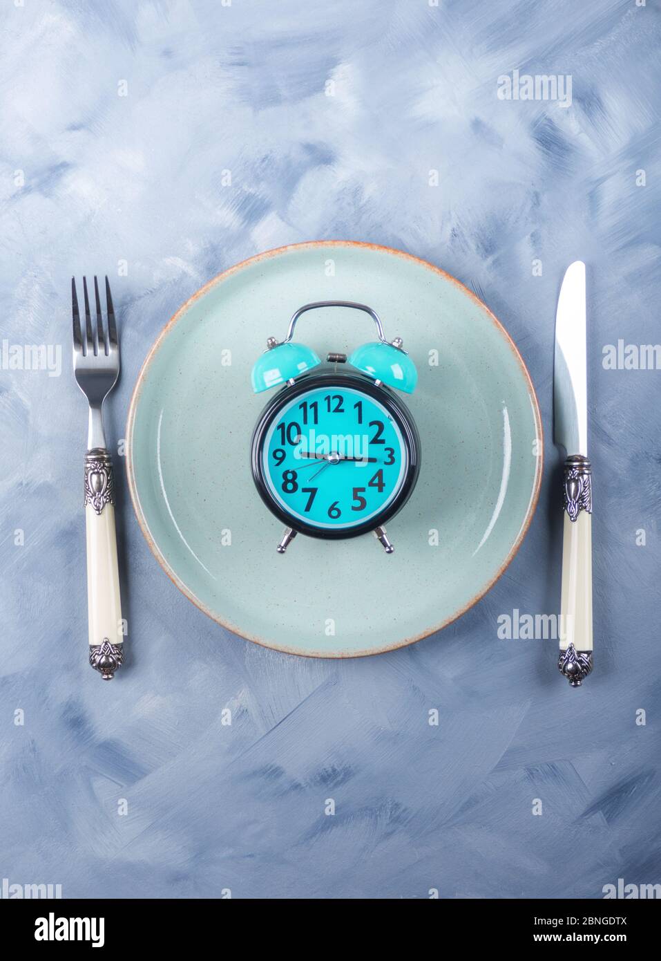 Concepto de ayuno intermitente con despertador azul Foto de stock