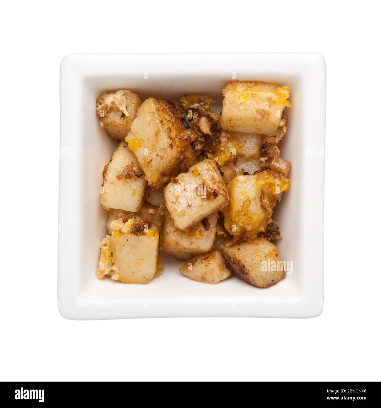 Cocina asiática - pastel de zanahoria frito en un tazón cuadrado aislado sobre fondo blanco Foto de stock