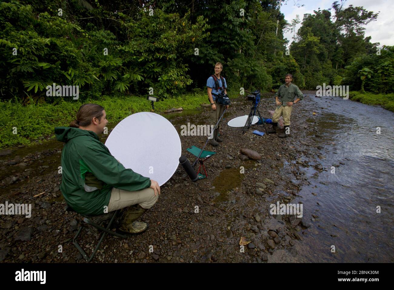 Eric Liner e Ian Fein entrevistan al ornitólogo Edwin Scholes en el borde del río en el bosque de tierras bajas cerca de Oransbari, Papúa Occidental, Nueva Guinea. Foto de stock