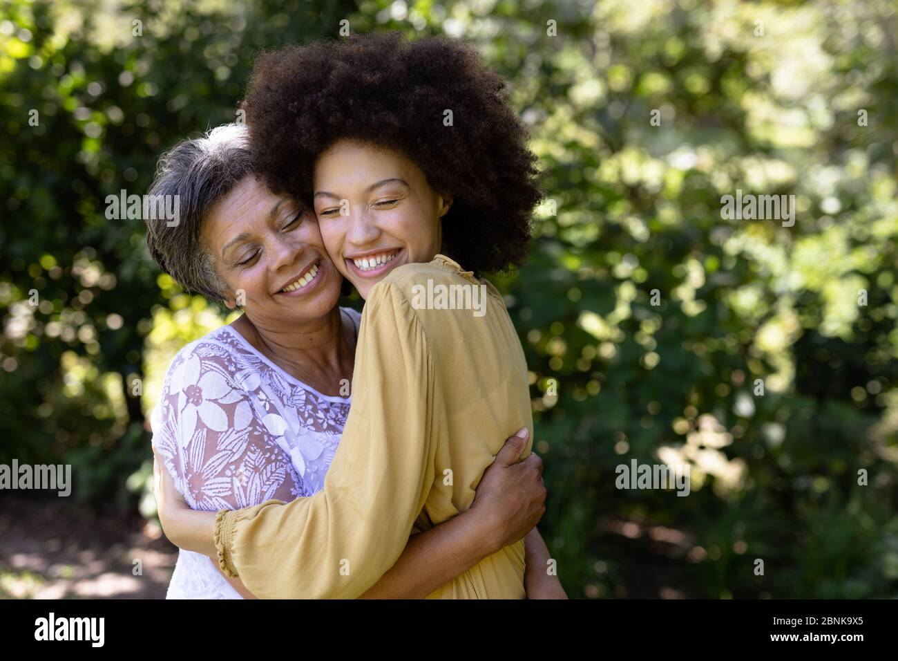 Mujer de raza mixta y su hija disfrutando de su tiempo en un jardín Foto de stock