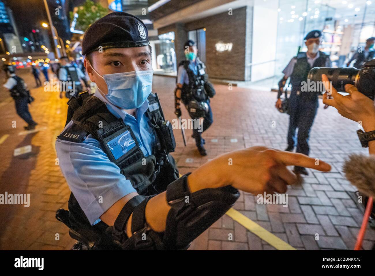 Un agente de policía se enfrenta a los manifestantes durante una vigilia en las afueras del centro comercial Pacific Place en la zona del Almirantazgo de Hong Kong para conmemorar el 11 aniversario desde que un hombre cayó a su muerte por un andamio, Durante una protesta contra el proyecto de ley de extradición del gobierno de Hong Kong el año pasado. Foto de stock