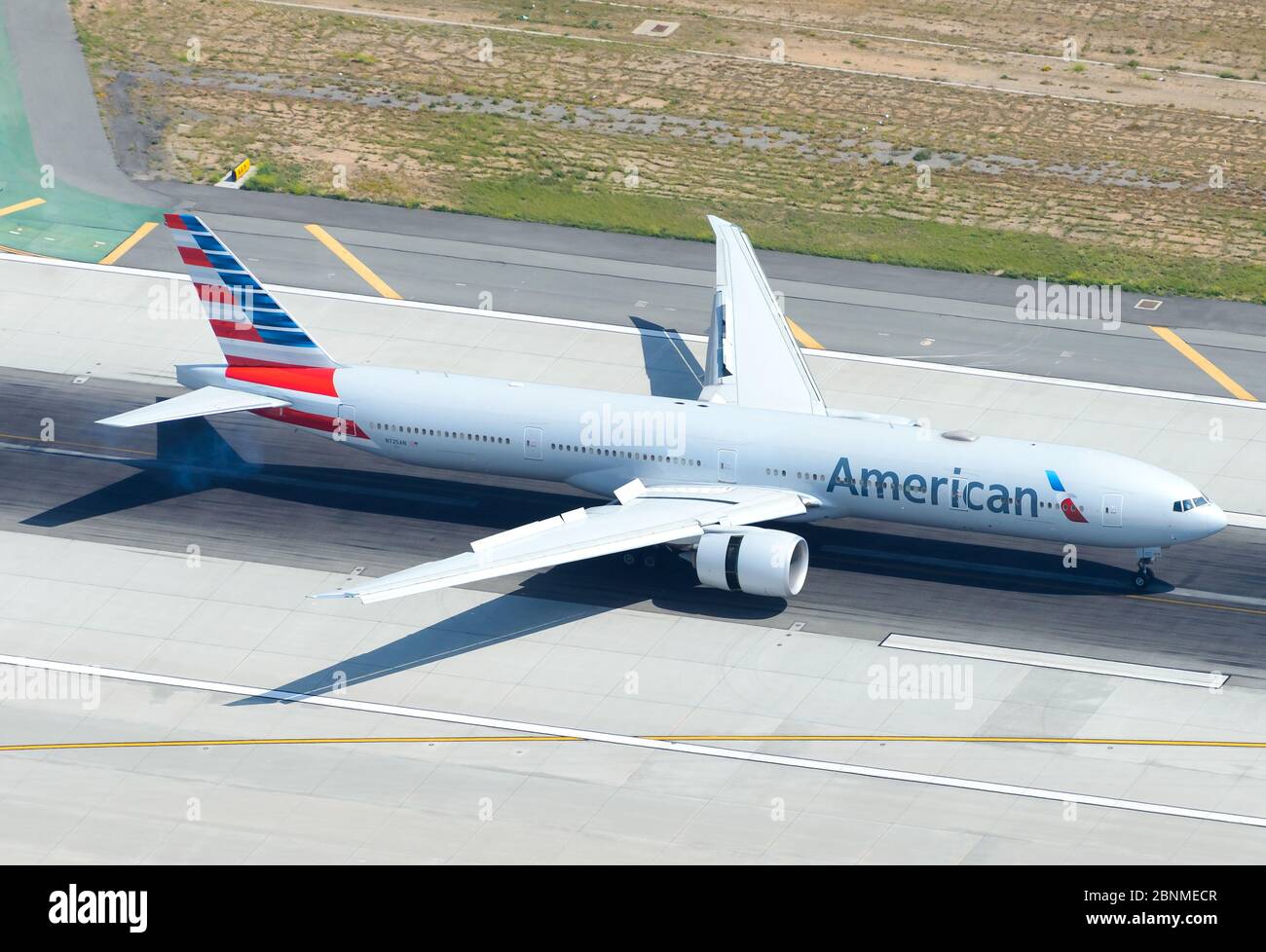 American Airlines Boeing 777 aterrizando en la pista del Aeropuerto Internacional de LAX con listones, solapas y empuje de retroceso de motor desplegados. 77W avión N725AN. Foto de stock