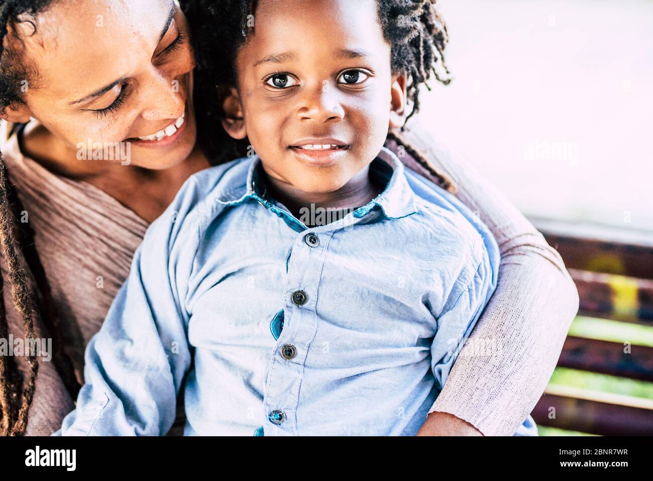 Familia amor concepto con afro negro madre y niños hijo pequeño juntos abrazando y sonriendo con felicidad - hermosa pareja momia y niño en actividades de ocio al aire libre Foto de stock