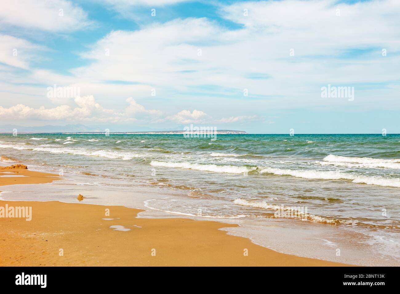 playa solitaria con mar cubierto de olas y cielo nublado Foto de stock