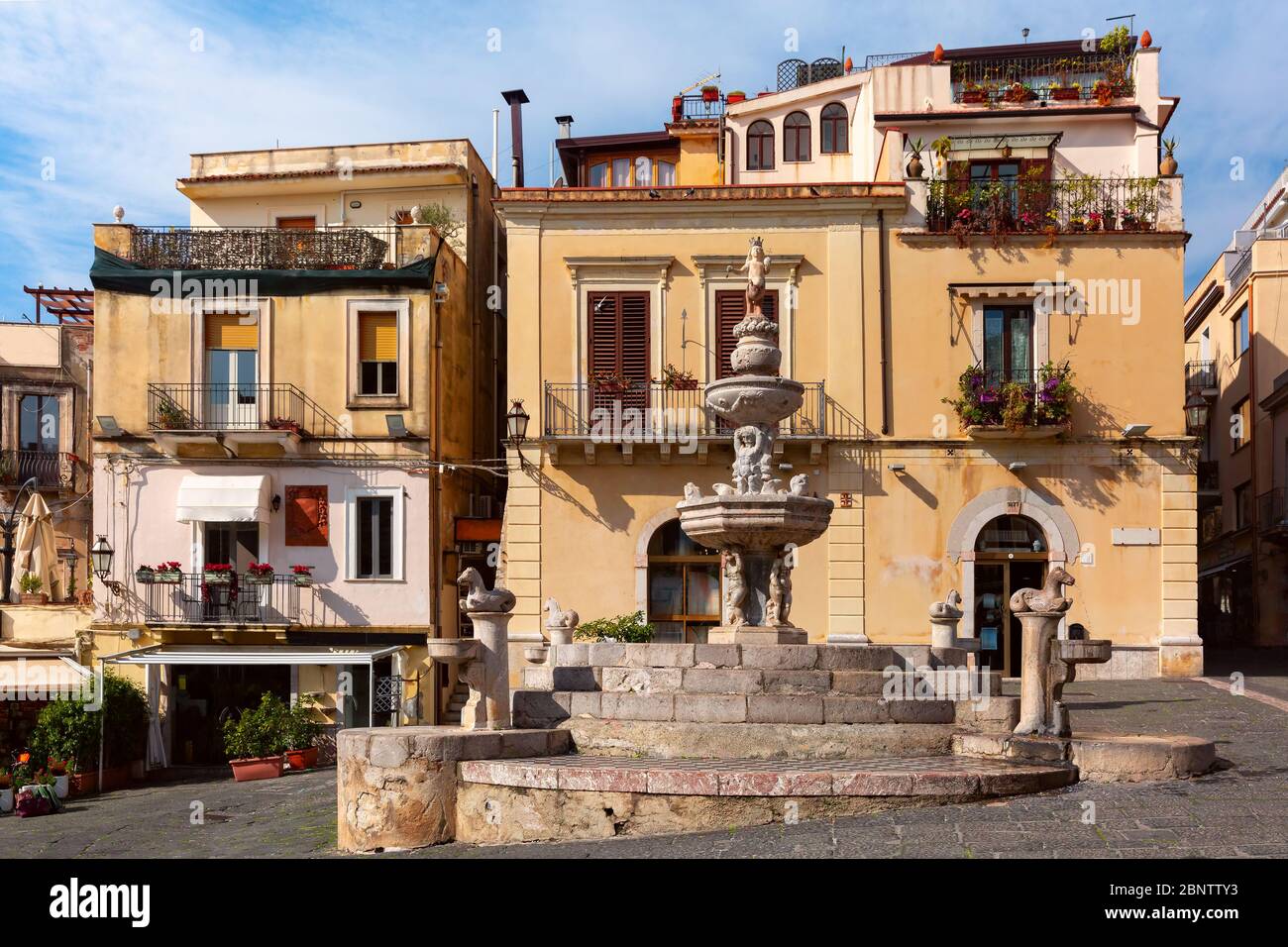 Fuente y casas típicas con restaurantes en la plaza Piazza Duomo en Taormina en la mañana soleada, Sicilia, Italia Foto de stock