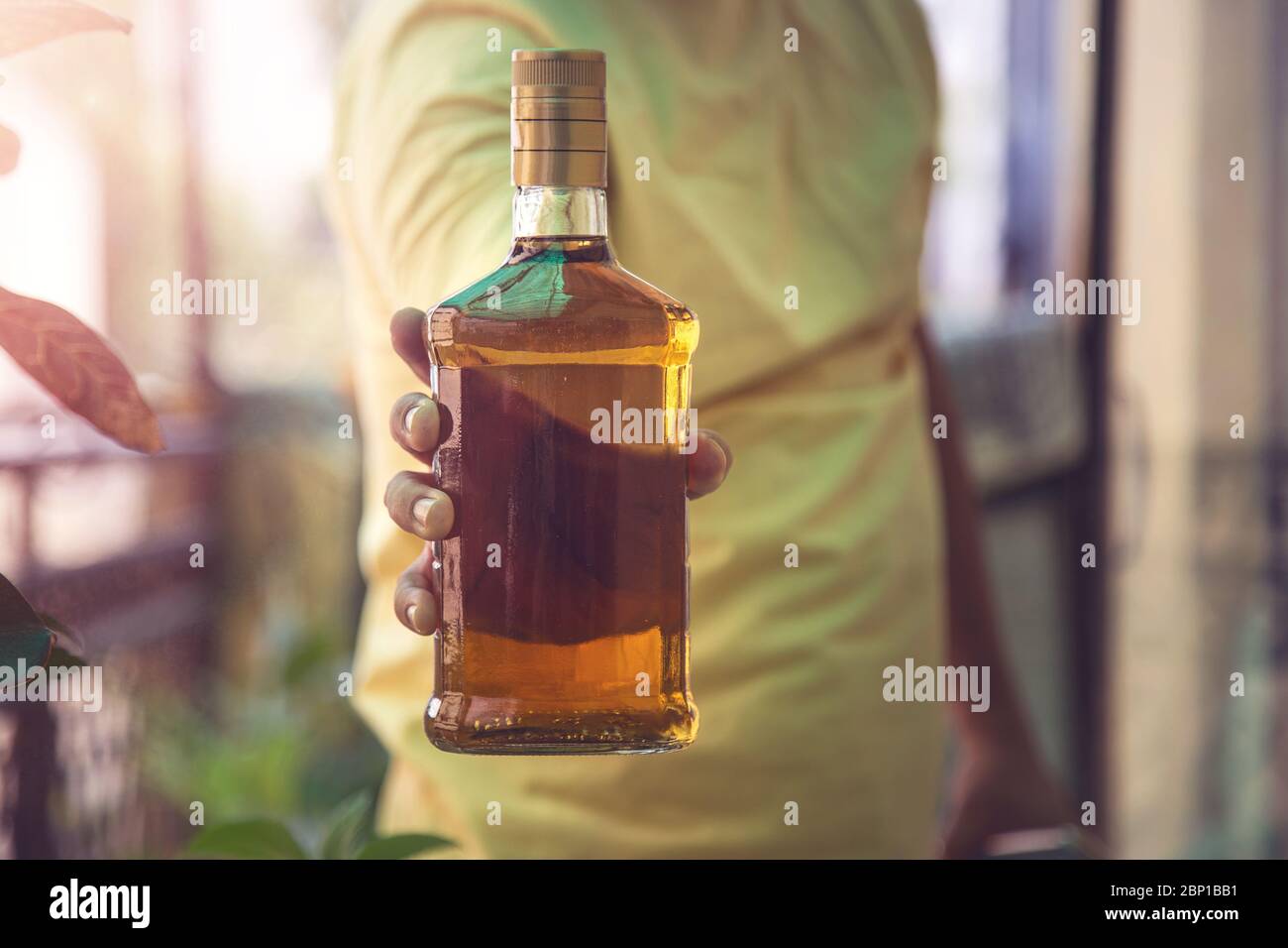 Primer plano de la mano del cliente mostrando la botella de licor de whisky cuando se va después de comprar licor de una tienda en medio de la continua cierre Covid-19 Foto de stock