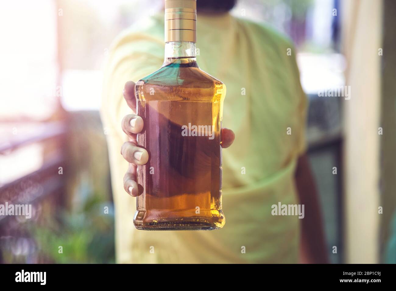 Primer plano de la mano del cliente mostrando la botella de licor de whisky cuando se va después de comprar licor de una tienda en medio de la continua cierre Covid-19 Foto de stock