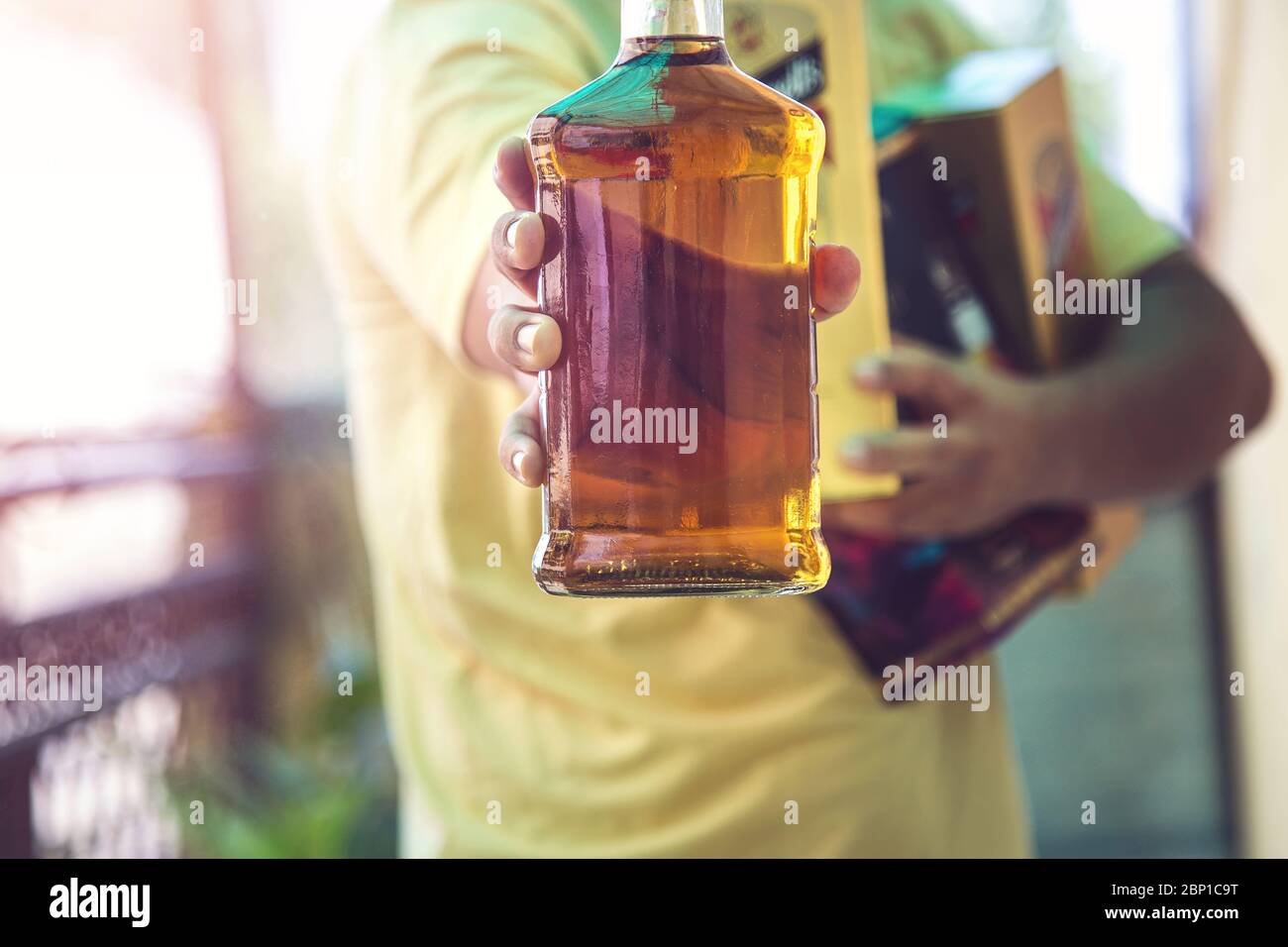 Primer plano de la mano del cliente mostrando la botella de licor de whisky cuando se va después de comprar licor de una tienda en medio de la continua cierre Covid-19 Foto de stock