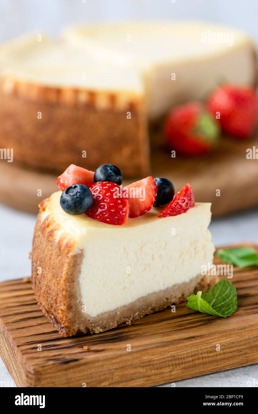 Una rebanada de tarta de queso con bayas de verano sobre tabla de madera. Tarta de queso sabrosa Foto de stock